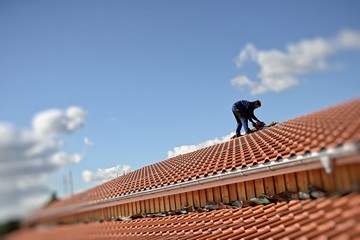 Freiplatz Text Himmel, Silhouette Dachdecker Bau Arbeiter in blauer Jacke auf rotem Dachziegel Dach unter freiem Himmel in der Sonne