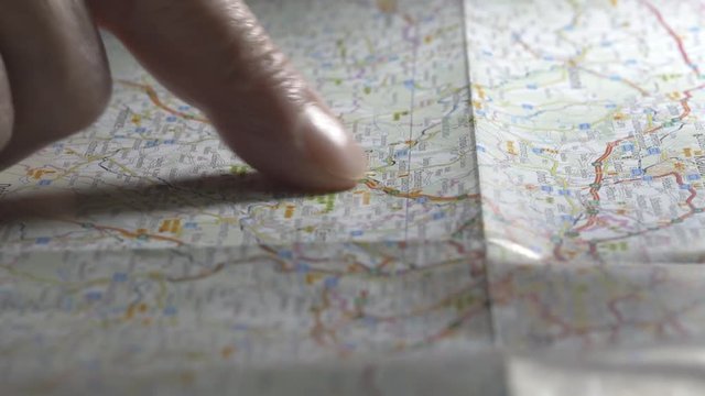 Man Traces Route On Map Reading And Taps A Spot