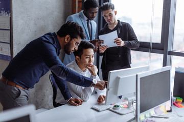 Group of strategy managers reading last business reports from exchanges on laptop and pesonal...