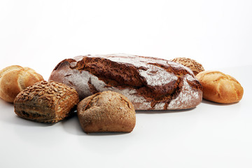 Different kinds of bread and bread rolls on board from above.