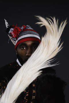 Portrait of man in traditional clothing standing against black background