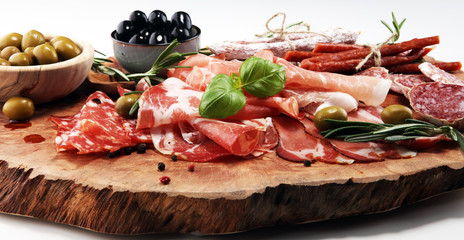 Marble cutting board with prosciutto, bacon, salami and sausages on wooden background. Meat platter