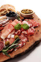 Marble cutting board with prosciutto, bacon, salami and sausages on wooden background. Meat platter
