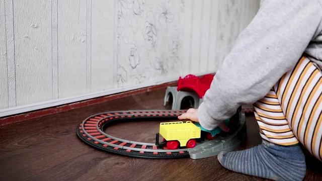 A little boy plays a children's railway. Mom is watching her son from above. The child is fascinated by the train