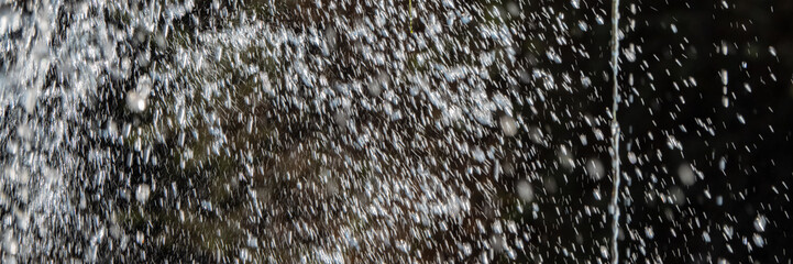 splashes and drops of water in motion on a dark background.