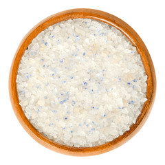 Persian Blue Salt in wooden bowl. Fine rock salt from Iran. The blue color occurs during forming the crystalline structure, caused by an optical illusion. Seasoning. Food photo, closeup, over white.