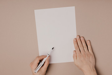 Hands writing on paper blank a4 size on grey background.