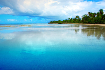 Tropical sea and blue sky background. Big clouds are reflected in the water.