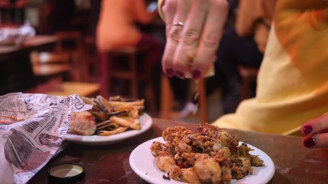 Young woman eat tapas fried octopus sitting in street gastro bar in Malaga Spain evening time