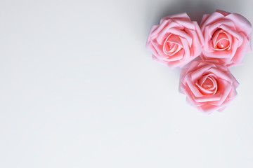 Plakat Top view of three pink roses arranged as a decor with copy space on white table for valentines or mothers day. Love concept.