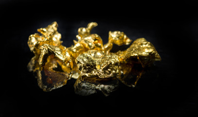 Several gold nuggets on a dark background. Selective focus.