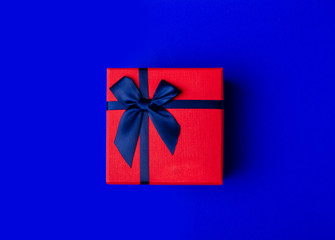 Red box gift with blue ribbon on blue background, top view fashion flat lay
