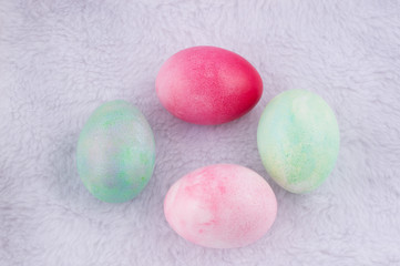 four multicolored painted Easter eggs on white artificial rabbit fur. holiday easter greeting card, poster, wallpaper