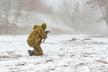 A military soldier in camouflage with a weapon goes on the offensive in winter.
