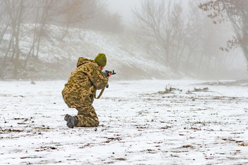 Naklejka premium A military soldier in camouflage with a weapon goes on the offensive in winter.
