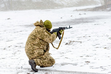 A combat soldier is aiming fire from a weapon, close-up.