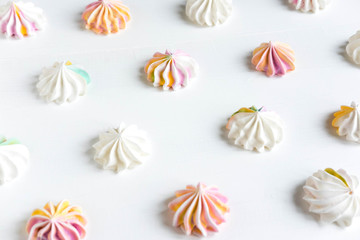 Pattern with meringues on a white wooden background. Multicolored meringues on a white background. Basis for confectionery banner, cafe, sweet shop. Meringue banner