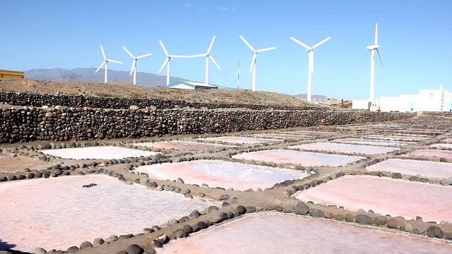 Pink salt mine squares with wind turbines on background in sunny day in Gran Canaria island, Spain. Industrial area, salt production factory in Canary Islands