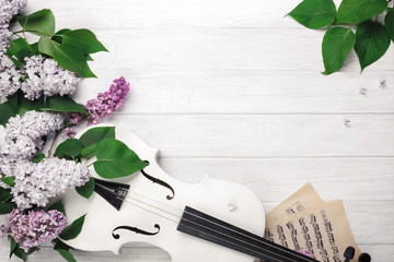 A bouquet of lilacs with violin and music sheet on a white wooden table. Top wiev with space for your text