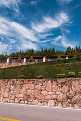 Beautiful big residence surrounded by bushes and brick walls in the middle of a road in the forest 