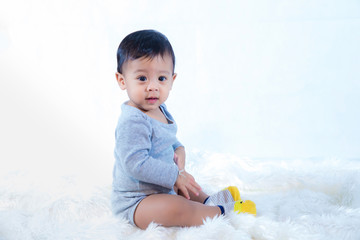 smile baby boy is shooting in the studio. fashion image of baby and family. Lovely baby sit down on a soft white carpet. image for background, wallpaper, copy space, objects, fashion and article