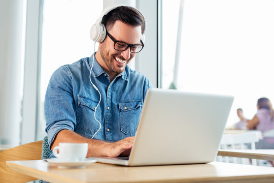 Businessman Listening To Music By Headphones While Working With Laptop Computer In Co Working Space. - Image