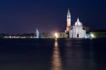 Night cityscape of Venice with illuminated church reflected in the waters of the canal.