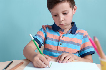 European boy carefully drawing with colorful pencils.