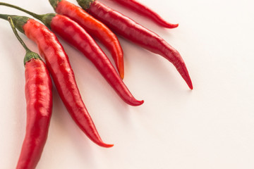 Red chili pods with green stems on a white background