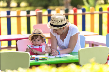 mom and little daughter drawing a colorful pictures