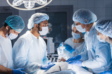 Surgery preparations. Surgical team preparing their patient for surgery adjusting oxygen mask on...