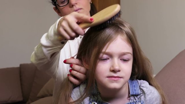 Daughter start smiling when mother combing her hair