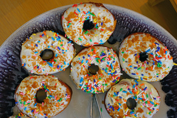 Fresh donuts with white icing and colorful sprinkles