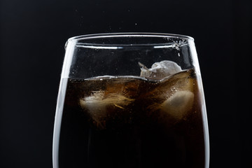A glass of cola beverage with a salt. On a black background.