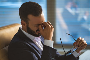 The businessman with headache sitting on a chair