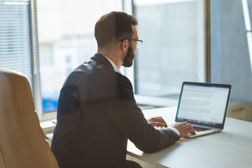 The businessman in glasses working with a laptop