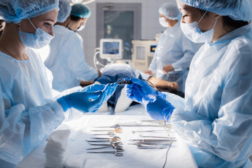 Two young Asian and Caucasian female assistants preparing surgical instruments and tools arranged...