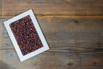 Pine nuts in white frame on old wooden background