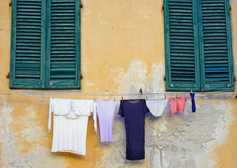 Colorful clothes hanging on a clothesline from a window to dry in the sun in Pisa, Italy 
