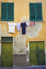 Colorful clothes hanging on a clothesline from a window to dry in the sun in Pisa, Italy 