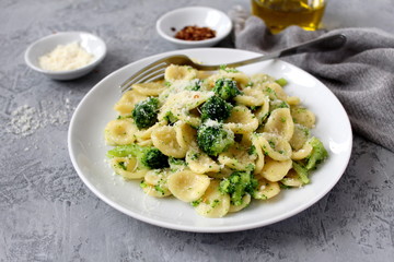 Homemade pasta orecchiette with broccoli, Parmesan cheese and chili pepper on light background. Top view with copy space.