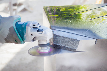Worker cutting stone block by cutter machine.