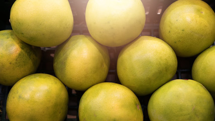Top view of several pomelos yellow green color lying in plastic box. Pomelos in the plastic box for sale in the market. Pattern of pomelos