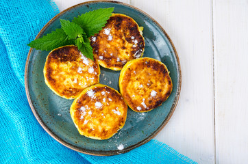 Plate with fritters on white wooden table
