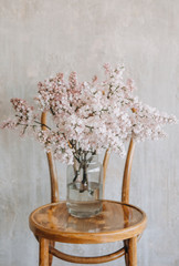 lilac flowers vase wooden chair textured wall