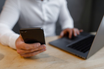 Portrait of Young man with a mobile phone sitting at cafe using laptop.