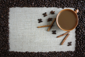 A cup of coffee surrounded by cinnamon, anise and coffee beans