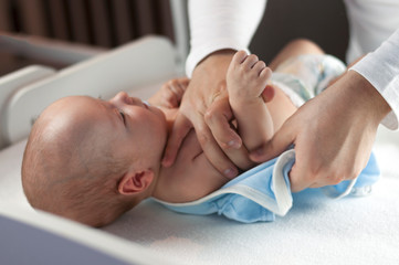 Young dad changes the diaper and clothes to his newborn small child. Selective focus.