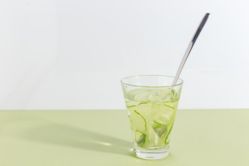 Glass cup with cucumber water on a light green background. Minimalistic creative concept. Copy space.