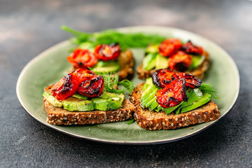 Avocado toasts with roasted tomatoes in a plate